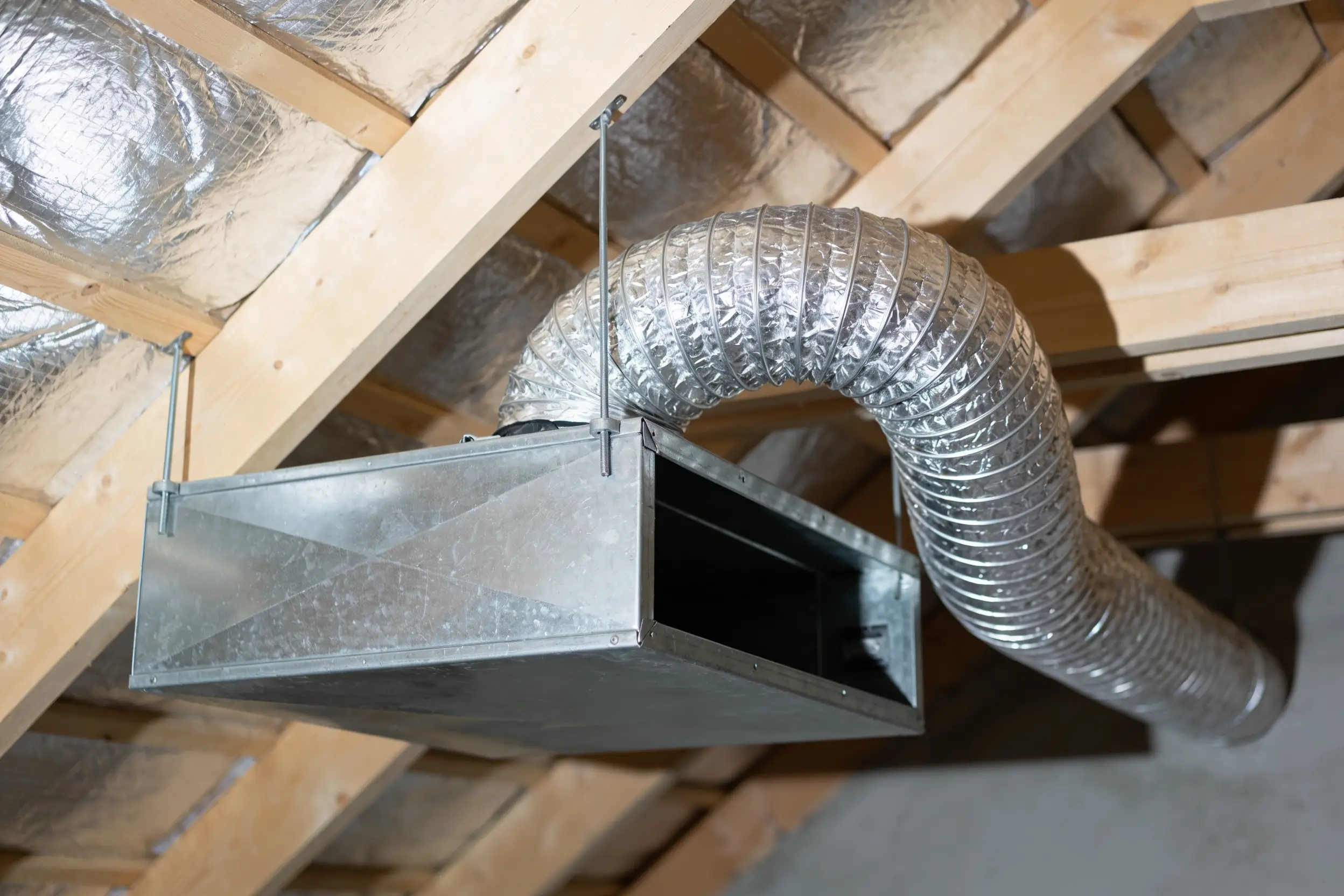 Insulated flexible duct runs and a sheet metal plenum in an attic space
