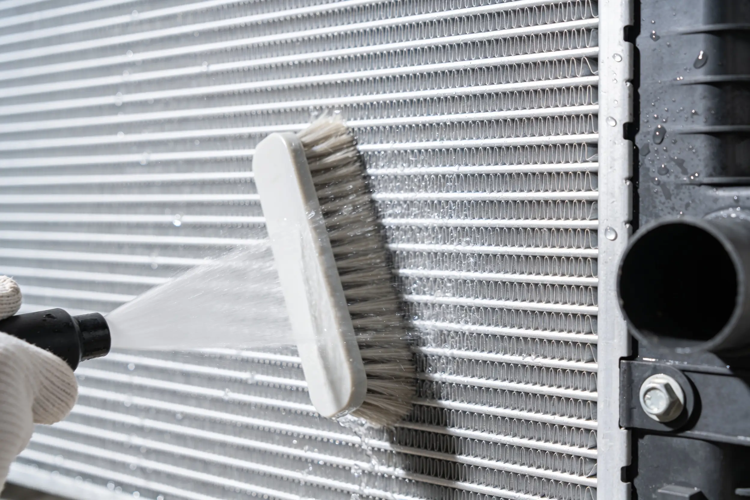 Condenser coil fins being cleaned with a soft brush and water